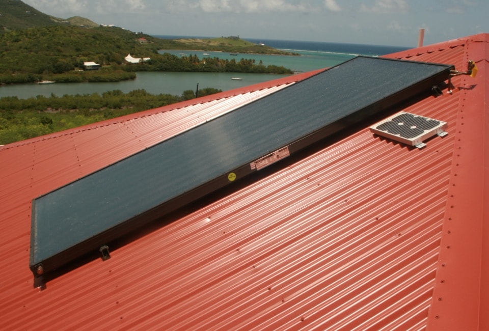 Solar thermal collectors on red metal roof with Caribbean coastline view