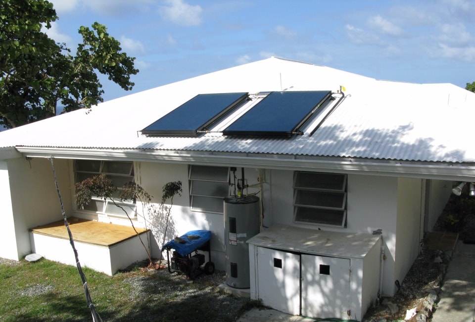 White residential building with dual solar hot water collectors and storage tank