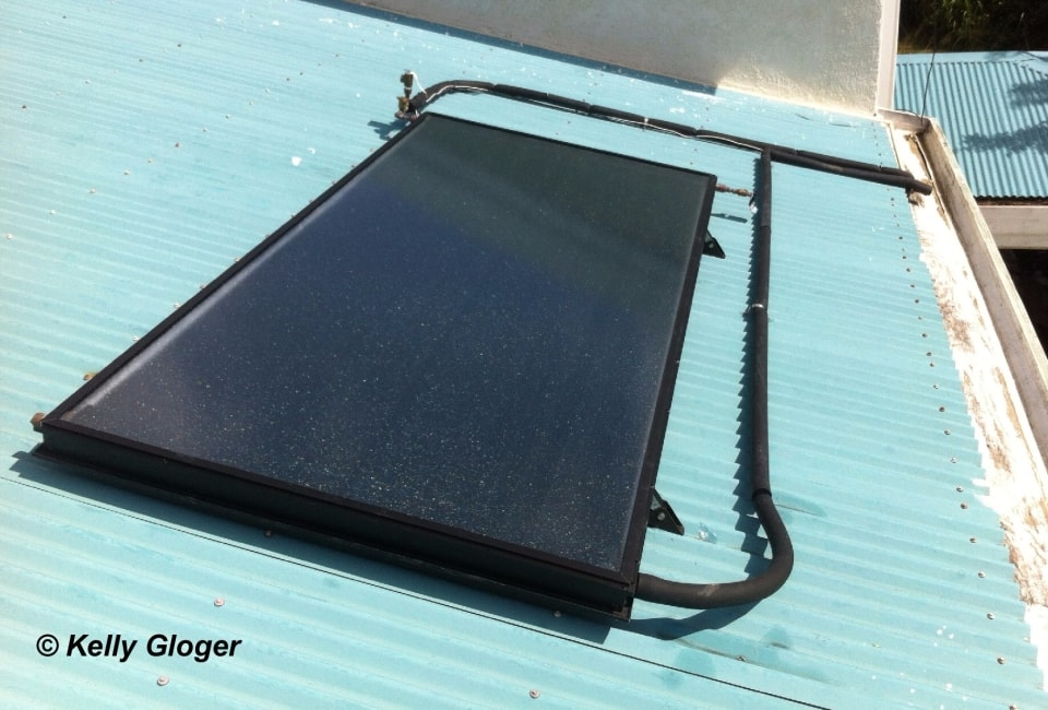 Close-up of flat-plate solar collector on blue corrugated roof
