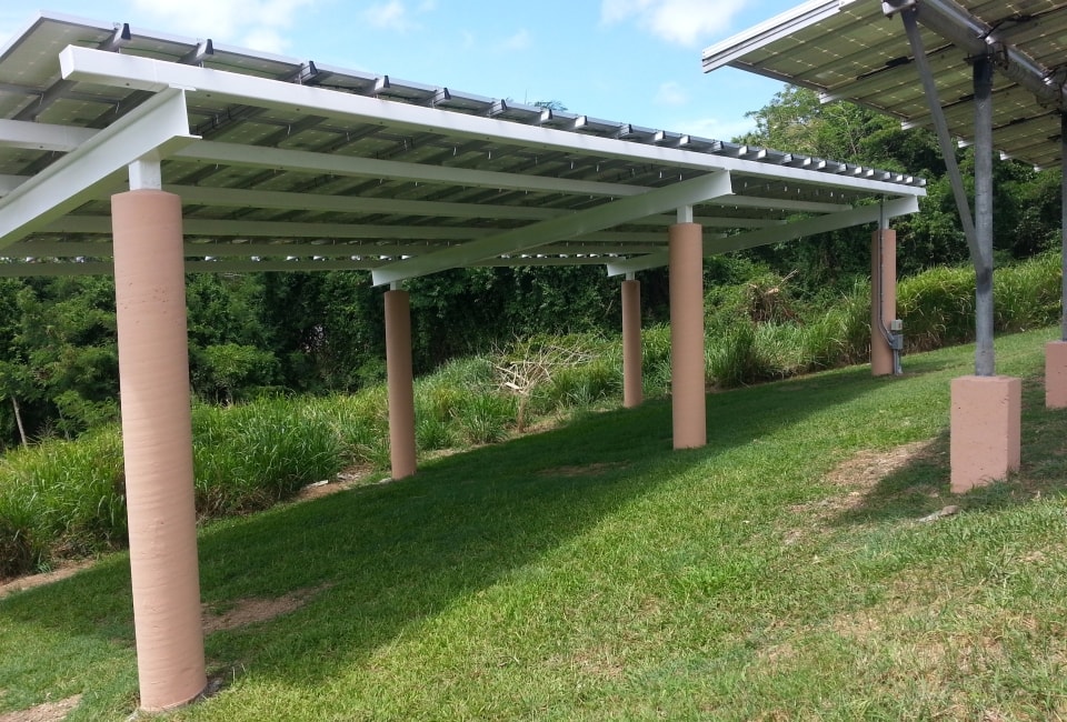 Solar PV pergola structure with panels mounted on concrete columns over green lawn
